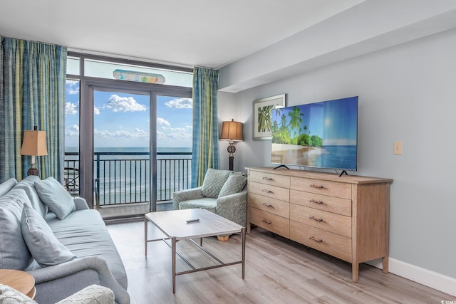 living room with expansive windows, light wood-type flooring, and a water view