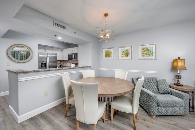 dining space with a chandelier and light wood-type flooring