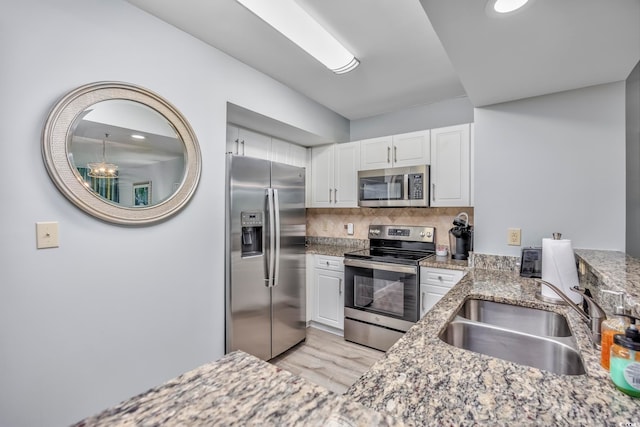 kitchen featuring tasteful backsplash, stainless steel appliances, light stone counters, sink, and white cabinetry