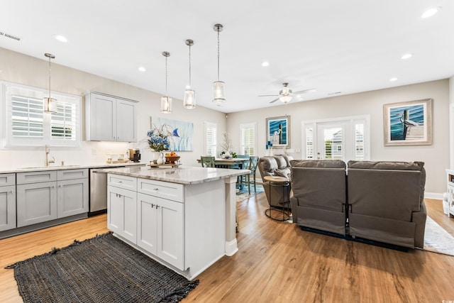 kitchen featuring pendant lighting, ceiling fan, a center island, and light wood-type flooring