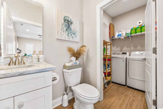 bathroom with wood-type flooring, vanity, toilet, and separate washer and dryer