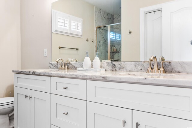 bathroom featuring oversized vanity, toilet, and dual sinks