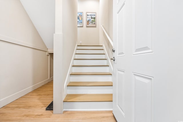 stairs featuring lofted ceiling and light wood-type flooring