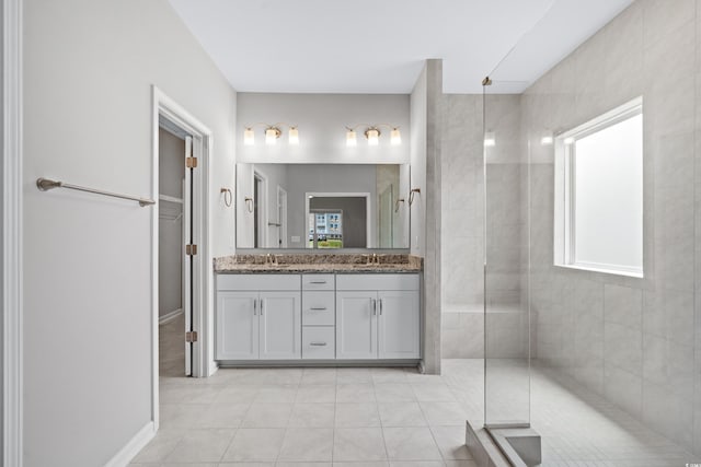 bathroom with a wealth of natural light, vanity, tile patterned floors, and a tile shower