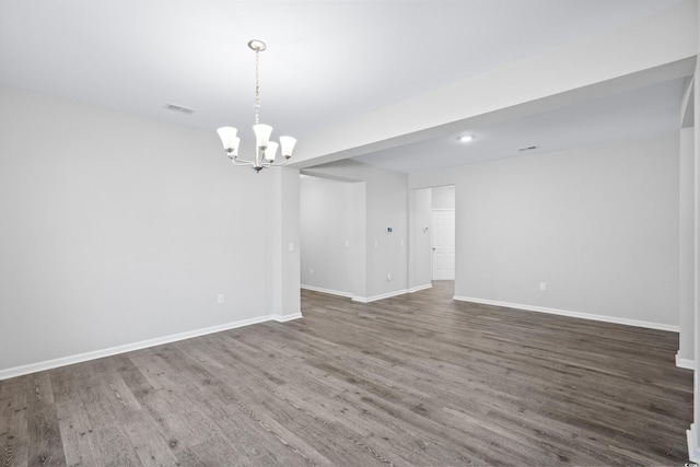 spare room with dark hardwood / wood-style floors and an inviting chandelier