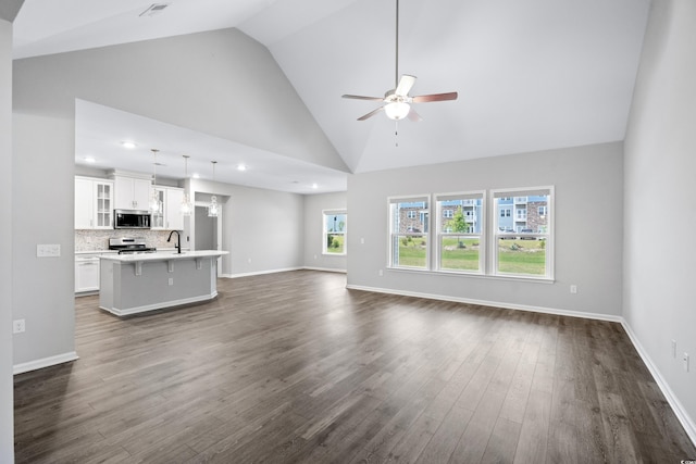 unfurnished living room featuring ceiling fan, high vaulted ceiling, sink, and dark hardwood / wood-style flooring