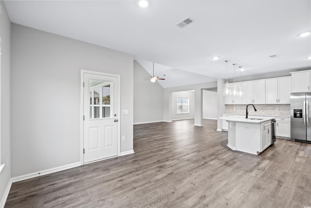 kitchen featuring appliances with stainless steel finishes, hanging light fixtures, a center island with sink, and white cabinets