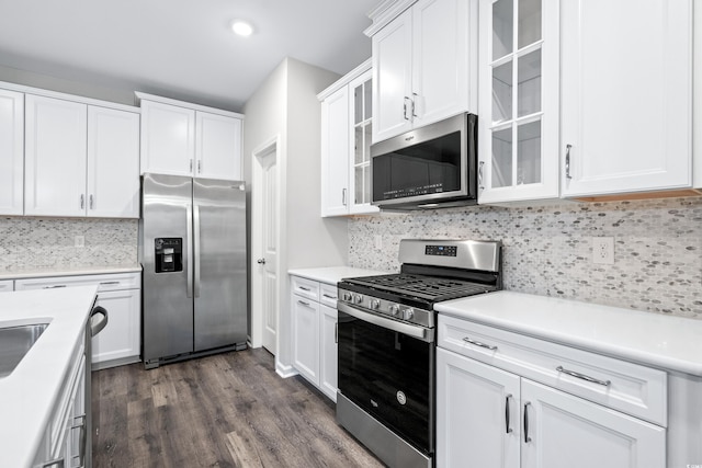 kitchen with white cabinetry, decorative backsplash, appliances with stainless steel finishes, and dark hardwood / wood-style floors