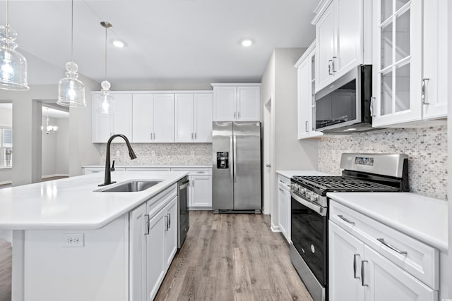 kitchen with a center island with sink, hanging light fixtures, sink, white cabinetry, and appliances with stainless steel finishes