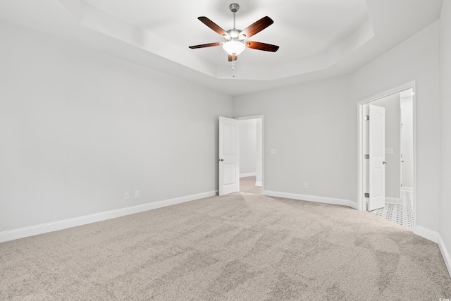 unfurnished room featuring light colored carpet, ceiling fan, and a tray ceiling