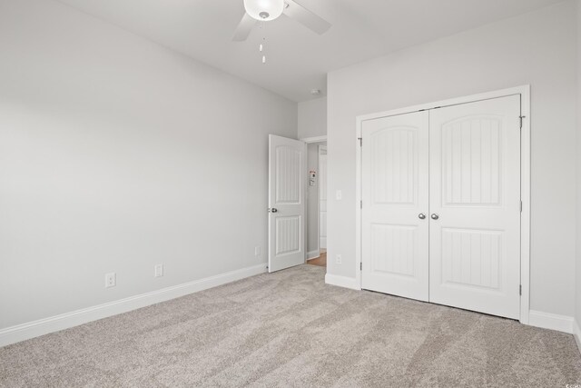 unfurnished bedroom featuring ceiling fan, a closet, and light carpet