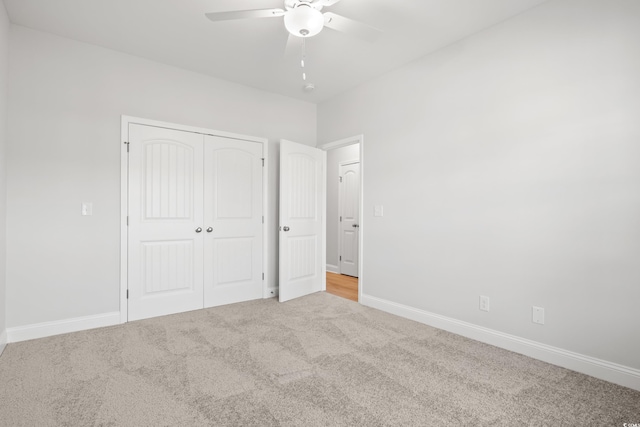 unfurnished bedroom with ceiling fan, light colored carpet, and a closet