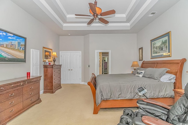 carpeted bedroom with a closet, a raised ceiling, ceiling fan, and ornamental molding