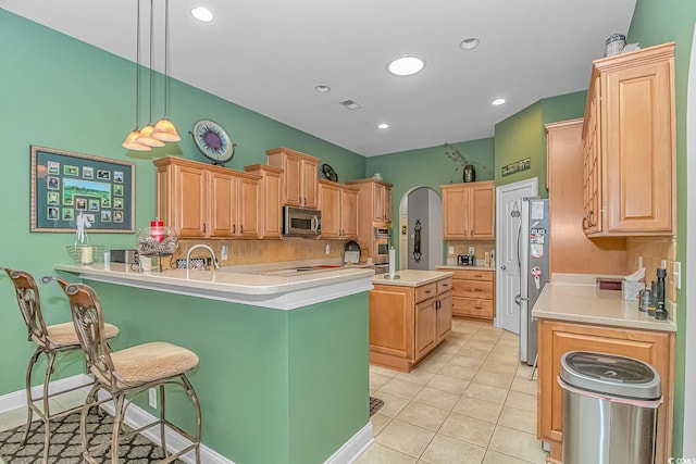 kitchen featuring pendant lighting, a breakfast bar, a kitchen island with sink, light tile patterned flooring, and stainless steel appliances