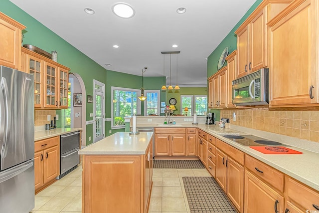 kitchen with appliances with stainless steel finishes, a center island, light tile patterned floors, and hanging light fixtures