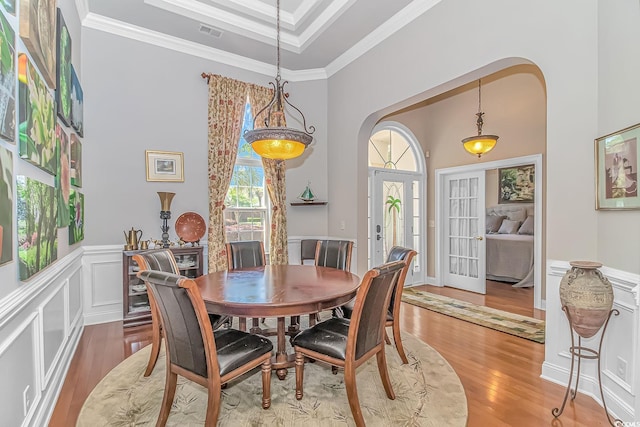 dining area with french doors, a tray ceiling, light hardwood / wood-style flooring, and ornamental molding