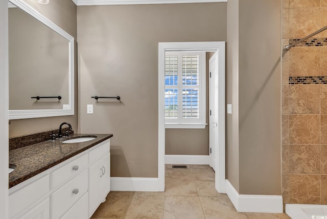 bathroom with tile patterned flooring, a tile shower, and vanity