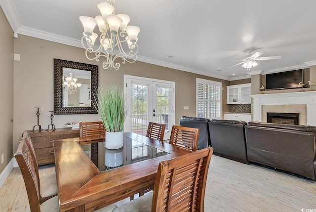 dining room featuring ceiling fan with notable chandelier, light wood-type flooring, crown molding, and french doors