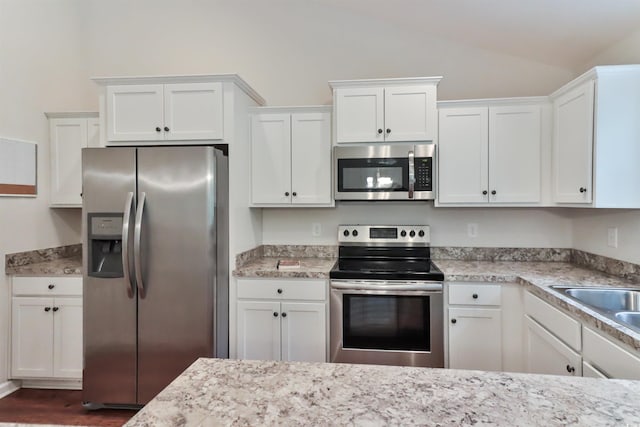 kitchen with white cabinets, stainless steel appliances, lofted ceiling, and sink