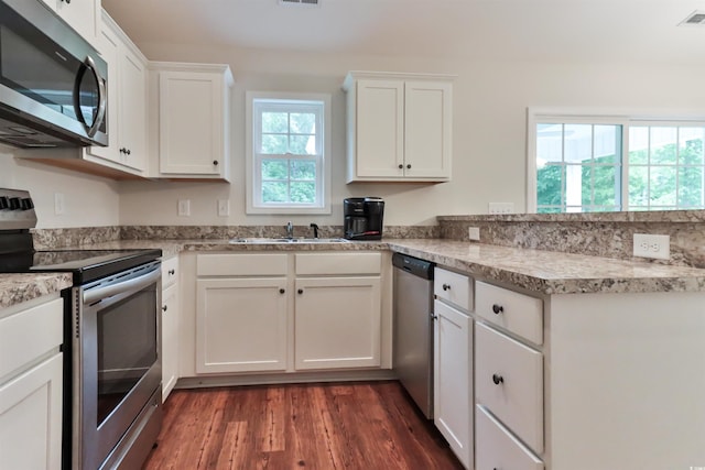 kitchen featuring light stone countertops, appliances with stainless steel finishes, sink, white cabinets, and dark hardwood / wood-style floors