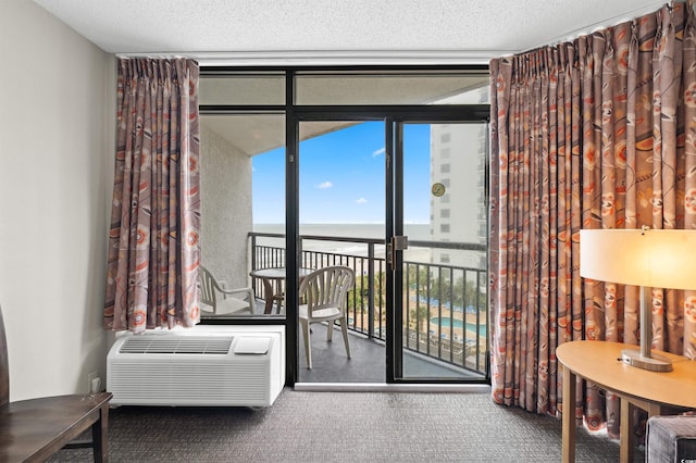 interior space featuring a textured ceiling, carpet, a wall mounted air conditioner, expansive windows, and a water view