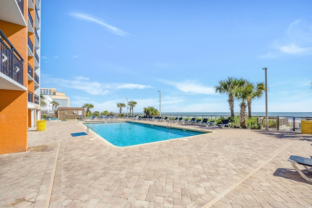 view of swimming pool featuring a water view and a patio area