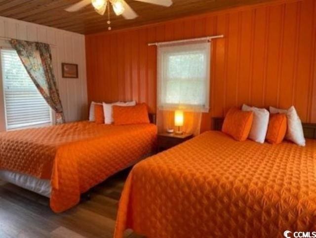 bedroom featuring ceiling fan, hardwood / wood-style flooring, wooden ceiling, and wooden walls