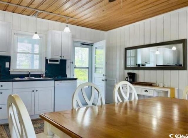 dining area with a healthy amount of sunlight, wooden ceiling, sink, and wooden walls