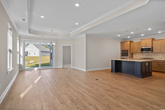 kitchen featuring ornamental molding, appliances with stainless steel finishes, an island with sink, and light hardwood / wood-style flooring