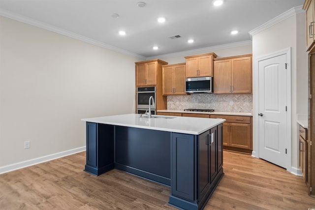 kitchen with a center island with sink, sink, appliances with stainless steel finishes, wood-type flooring, and crown molding