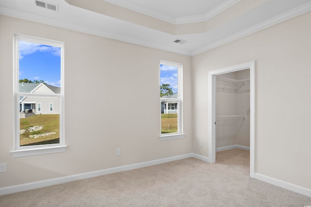 unfurnished bedroom with a closet, a walk in closet, multiple windows, and ornamental molding