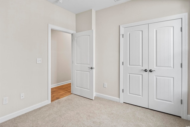 unfurnished bedroom featuring a closet and light colored carpet