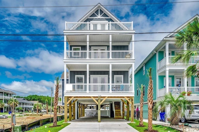coastal home featuring a balcony, french doors, board and batten siding, driveway, and a carport