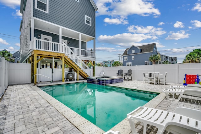 view of pool with stairway, a pool with connected hot tub, a fenced backyard, and a patio area