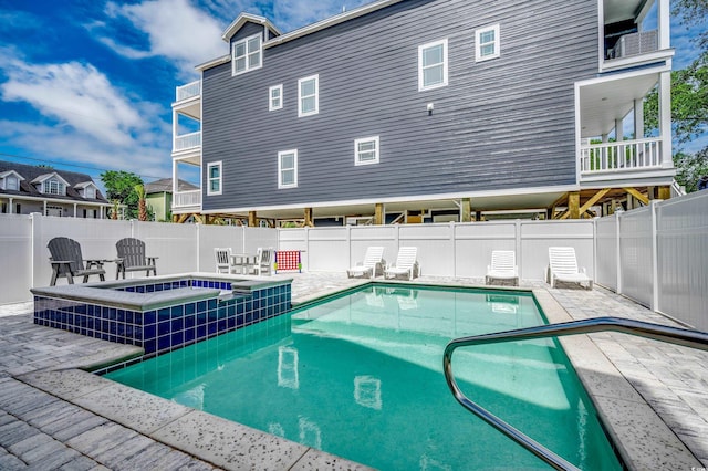 view of swimming pool featuring a pool with connected hot tub, fence, and a patio area