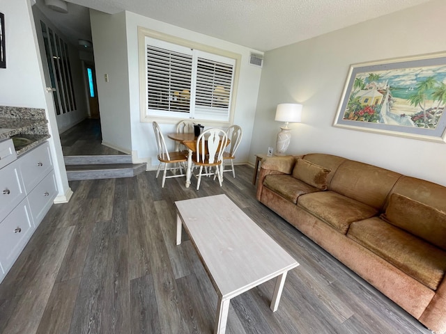 living room with dark wood-type flooring and a textured ceiling