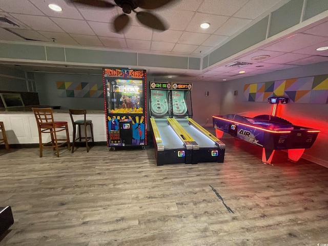 rec room with ceiling fan, a drop ceiling, wood finished floors, and visible vents