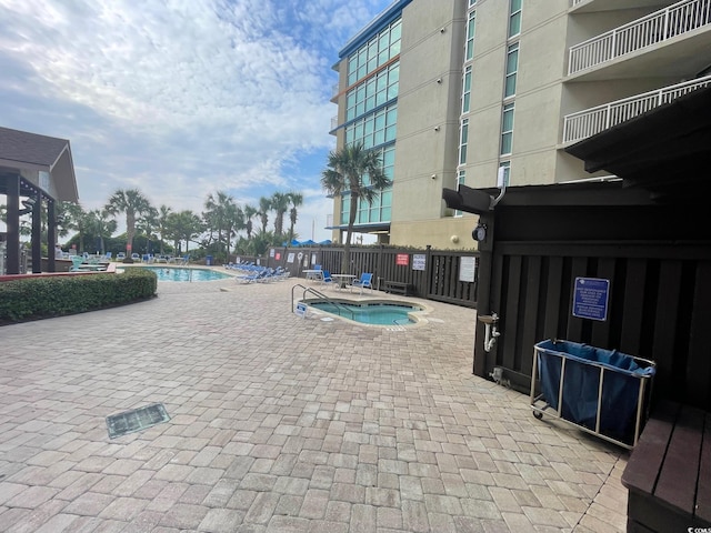 community pool featuring fence, a community hot tub, and a patio