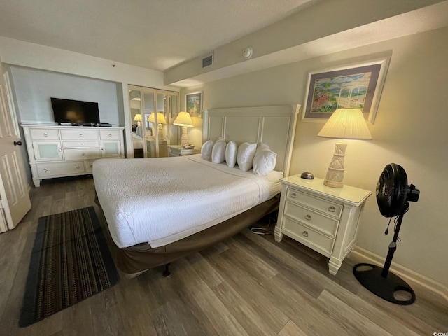 bedroom with wood finished floors, visible vents, and baseboards