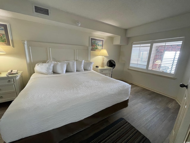 bedroom with a textured ceiling and dark wood-type flooring