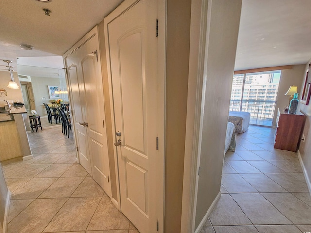 hallway featuring a textured ceiling, a wall of windows, and light tile patterned flooring