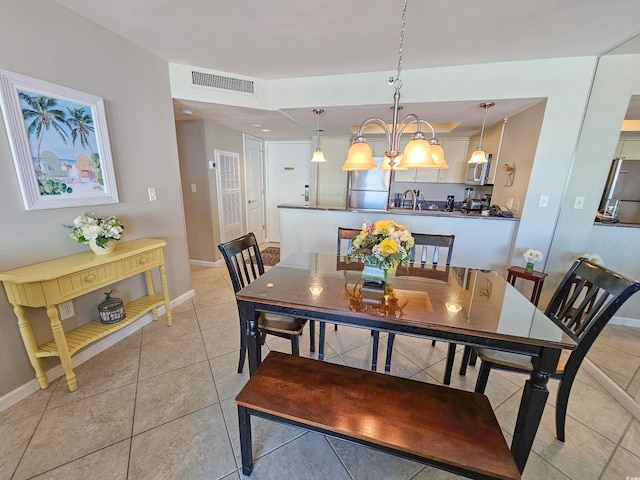 tiled dining room featuring sink and a chandelier