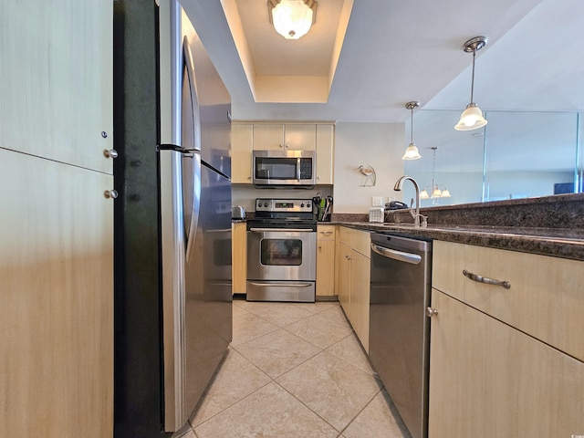 kitchen featuring stainless steel appliances, a raised ceiling, light tile patterned floors, light brown cabinetry, and hanging light fixtures