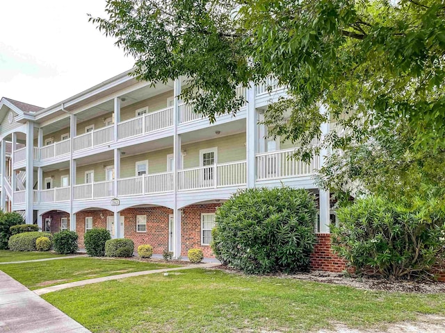 exterior space featuring a front lawn and a balcony