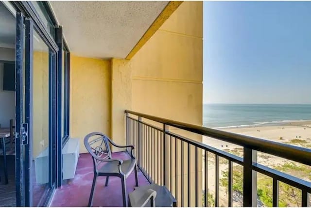 balcony featuring a view of the beach and a water view