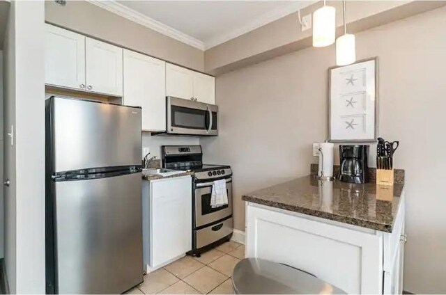 kitchen featuring stainless steel appliances, dark stone countertops, white cabinets, and pendant lighting