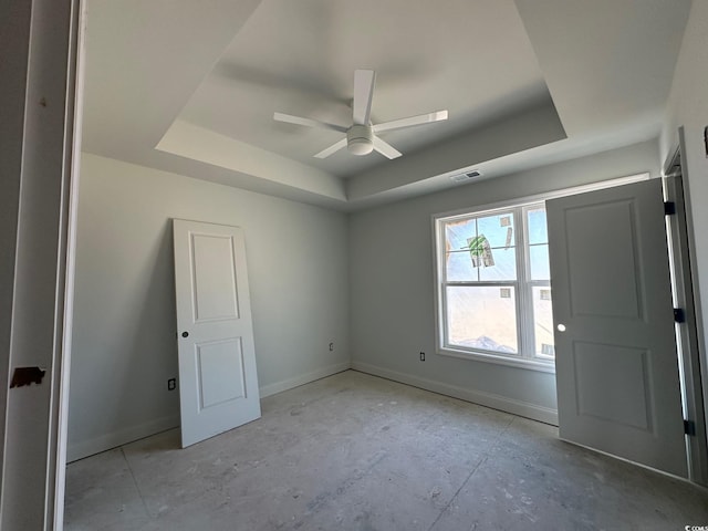 empty room featuring a tray ceiling and ceiling fan