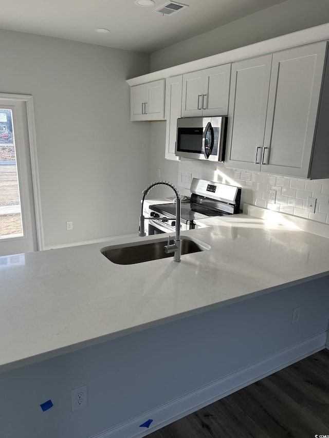 kitchen featuring sink, stainless steel appliances, dark hardwood / wood-style floors, backsplash, and white cabinets