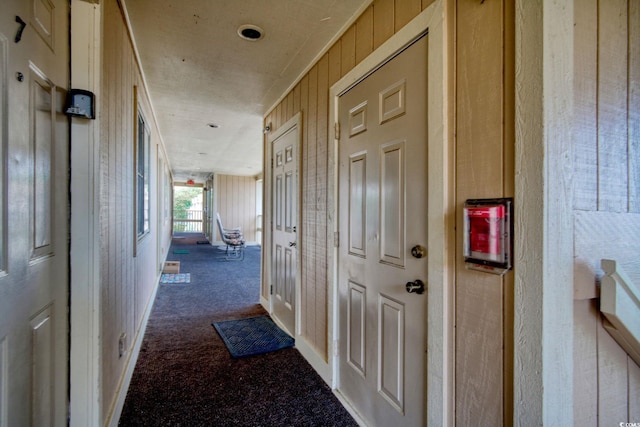 hallway with carpet flooring and wooden walls