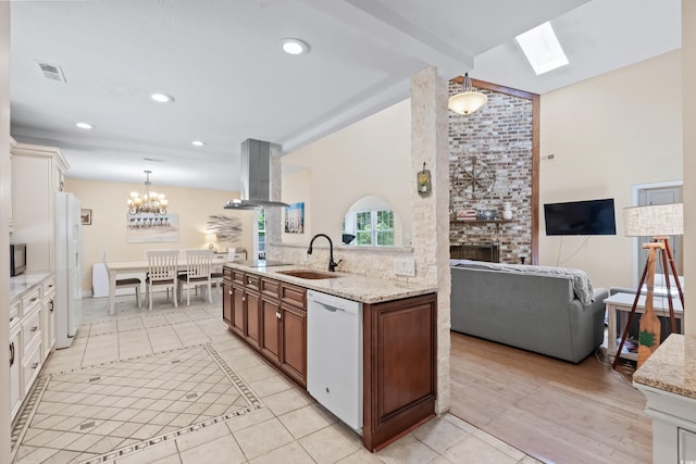 kitchen with white appliances, white cabinets, sink, a brick fireplace, and island exhaust hood